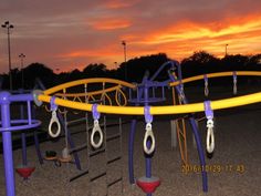 an empty playground at sunset with swings and rings