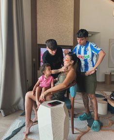 a group of people standing around a woman sitting in a chair with two children on her lap