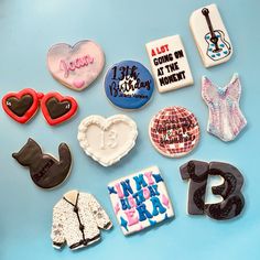 there are many different decorated cookies on the blue table together, including one with an i love rock and another with a guitar