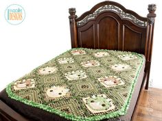 a bed with a green bedspread on top of it and a wooden headboard