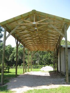 an outdoor covered area in the middle of a field with grass and trees around it