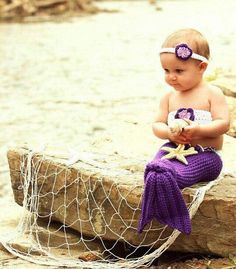 a little baby sitting on top of a rock