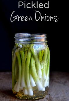 pickled green onions in a mason jar with text overlay that reads pickled green onions