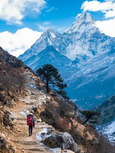 a person walking up a trail in the mountains with a mountain behind them and snow on the ground