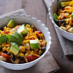 a white bowl filled with corn, avocado and black eyed peas next to a spoon