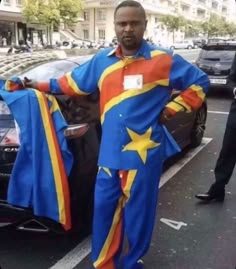 a man standing in front of a car with a flag on it's jacket