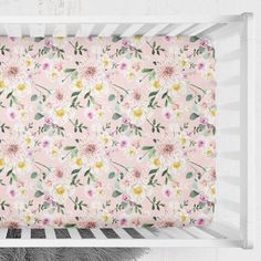 a baby crib with pink and yellow flowers on it