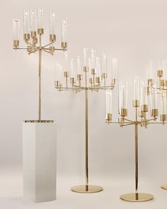 a group of gold and white candlesticks on display in front of a white wall