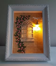 a white frame with pink flowers on it and a light in the window behind it