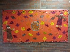 a bulletin board is decorated with fall leaves and a scarecrow on the front wall