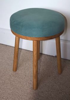 a green stool sitting on top of a carpeted floor next to a white wall