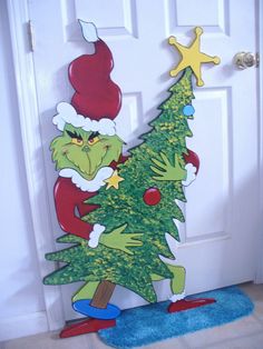 the grinch is standing in front of the door with a christmas tree on it