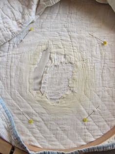 an unfinished piece of cloth with yellow pins on it and the letter d cut out