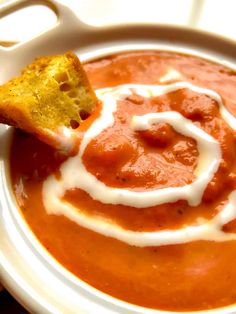 a white plate topped with soup and a piece of bread