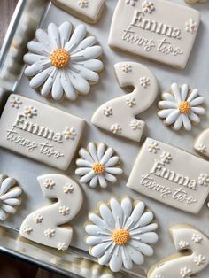 decorated cookies in the shape of numbers and daisies are on a tray with white frosting