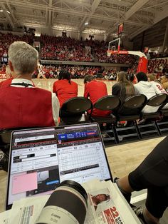 people are sitting in the bleachers with their laptops open and watching basketball