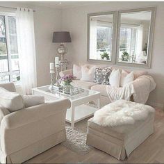 a living room filled with white furniture and pillows on top of a rug covered floor