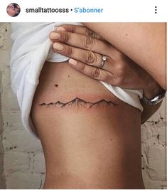 a woman's stomach with a mountain tattoo on it