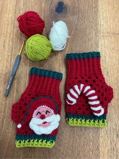 crocheted christmas mitts and balls of yarn on a wooden surface with scissors