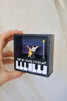 a person holding up a small card with an image of a dog and piano keys on it