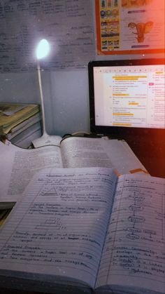 an open book sitting on top of a desk next to a computer monitor and keyboard