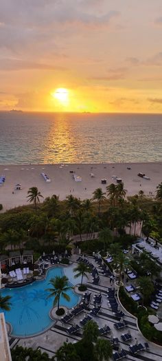 an aerial view of the beach and pool at sunset