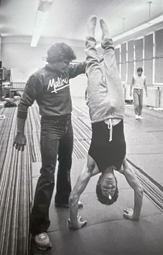 two people doing handstands in a gym