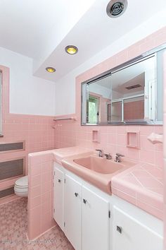 a bathroom with pink tiles and white cabinets