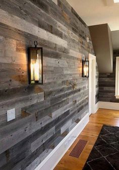 a wood paneled wall with two lanterns on it and a black rug in the middle