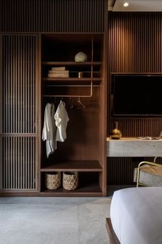 an open closet with clothes hanging on the wall and other items in baskets next to it