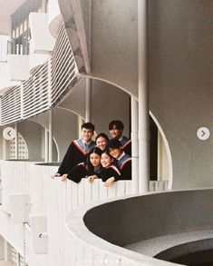 four people are posing for a photo in front of a white building with circular balconies