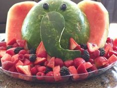 a watermelon shaped like an elephant surrounded by fruit