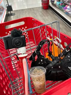 a red shopping cart filled with lots of different items next to a camera and cell phone