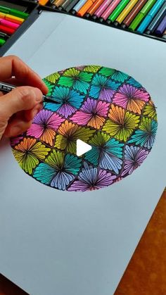 someone is drawing with colored pencils on paper