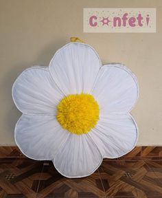 a large white flower shaped pillow sitting on top of a wooden floor next to a wall