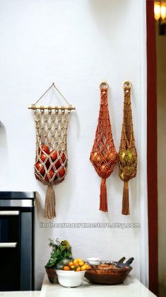 three macrame wall hangings on the wall above a bowl of oranges