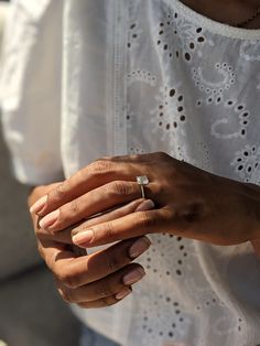 a close up of a person holding a ring on their finger and wearing a white shirt