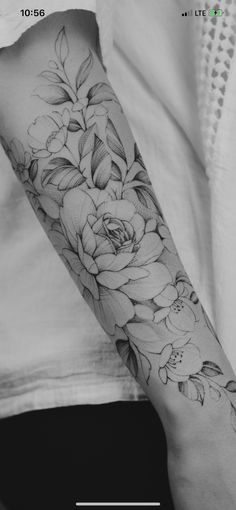 a black and white photo of a woman's arm with flowers on the forearm