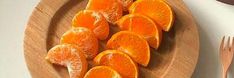 an orange cut in half on a wooden plate next to a fork and spoons