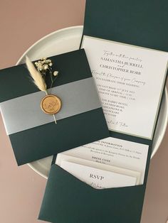 the wedding stationery is laid out on a white plate with a green and gray striped pocketfold