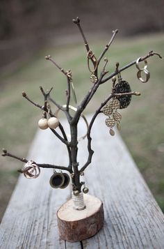 a tree that has some kind of jewelry on it's branches and is sitting on top of a piece of wood