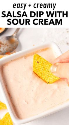 a hand dipping a tortilla chip into a bowl of salsa dip