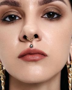 a close up of a woman with piercings on her nose and nose ring in front of her face