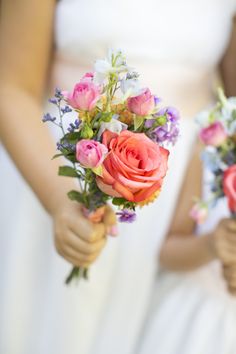 two bridesmaids holding bouquets of flowers in their hands at the same time