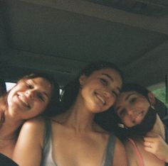 three women are sitting in the back of a car