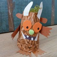 a craft made out of paper with scissors and grass in the mouth, sitting on top of a wooden table