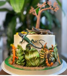 a cake decorated with lizards and plants on a table