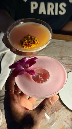 a person holding a pink plate with food on it and flowers in the bowl next to it