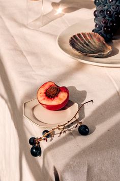 an apple and some grapes on a white table cloth with wine glasses in the background