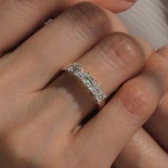 a woman's hand with a diamond ring on her left and an emerald in the middle